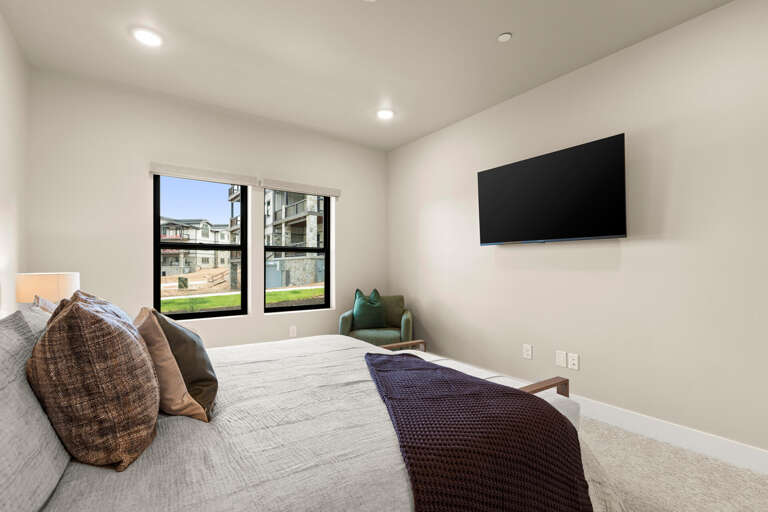 Sink into your plush bed and unwind in this peaceful bedroom, where natural light streams through large windows and a wall-mounted TV awaits your favorite shows.