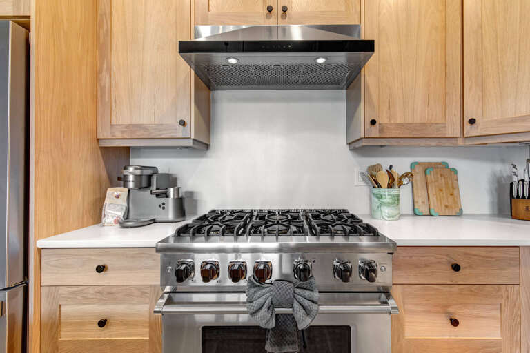 Cook your favorite meals on a professional-grade gas range in this beautifully appointed kitchen with warm wood cabinetry and modern stainless appliances.