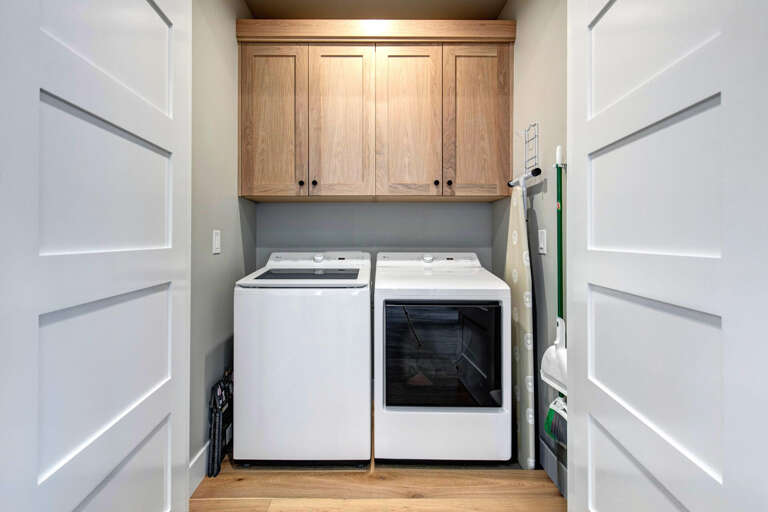Your own dedicated laundry room keeps chores simple, with a full-sized washer and dryer tucked beneath warm oak cabinetry for extra linens and supplies.