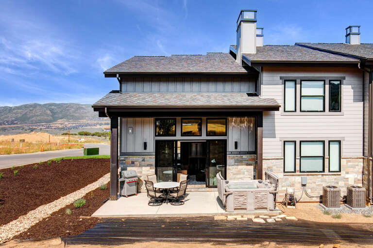 Modern mountain retreat with spacious patio and stunning natural landscape. The property sits in a peaceful setting with views of rolling hills and open terrain.