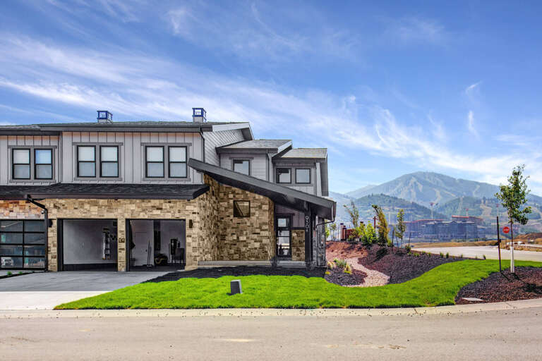 Modern property exterior with mountain backdrop and landscaped grounds, showcasing contemporary design and scenic surroundings.