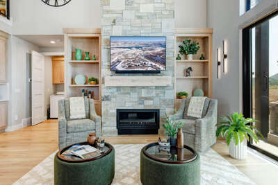 Unwind in your elegant living room, where a cozy fireplace and plush seating invite you to relax. The stone accent wall and built-in shelving add warmth, while natural light streams through the doors.