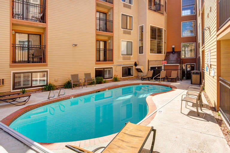 An outdoor pool area nestled within a residential complex featuring modern architecture and convenient access to surrounding units.