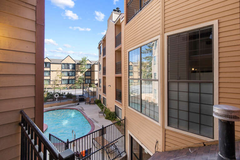 The property features an inviting courtyard area with a pool and hot tub, surrounded by well-maintained buildings and mature landscaping under sunny skies.
