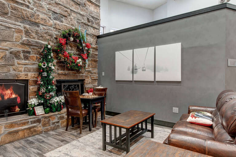 Relax in your cozy living space featuring a warm stone fireplace, comfortable leather sofa, and tasteful dÃ©corâperfect for unwinding after exploring the area.