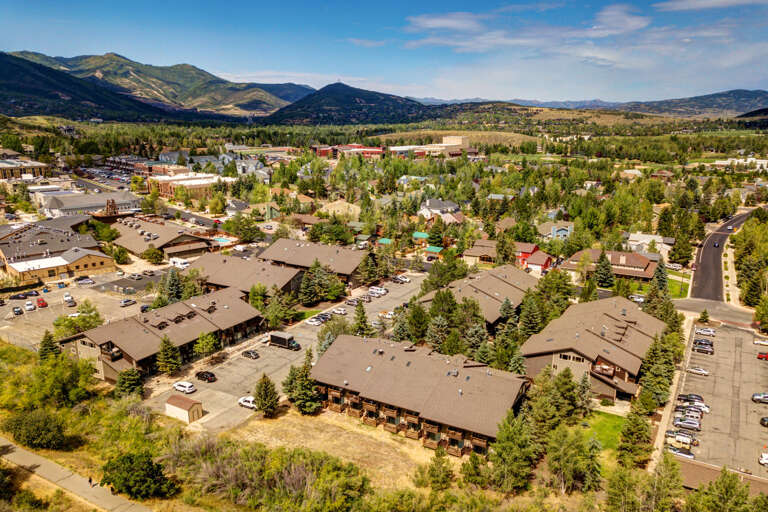 Aerial view of a mountain community with vacation rental properties nestled among evergreens, surrounded by scenic peaks and open valleys—part of the property's natural setting.