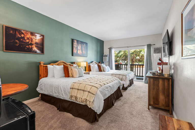 Unwind in your spacious retreat with two plush beds, layered with soft throws and pillows for ultimate comfort. Sunlight streams through the balcony doors, welcoming fresh mountain air.