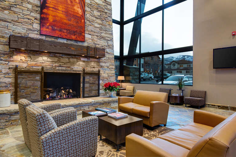 The main lobby welcomes you with warm textures, a glowing fireplace, and mountain views—perfect for relaxing before your next adventure.