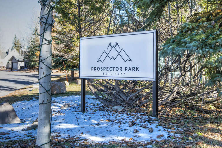 Prospector Park entrance marker set among aspen trees and evergreens, marking the arrival point to the property area established in 1977.