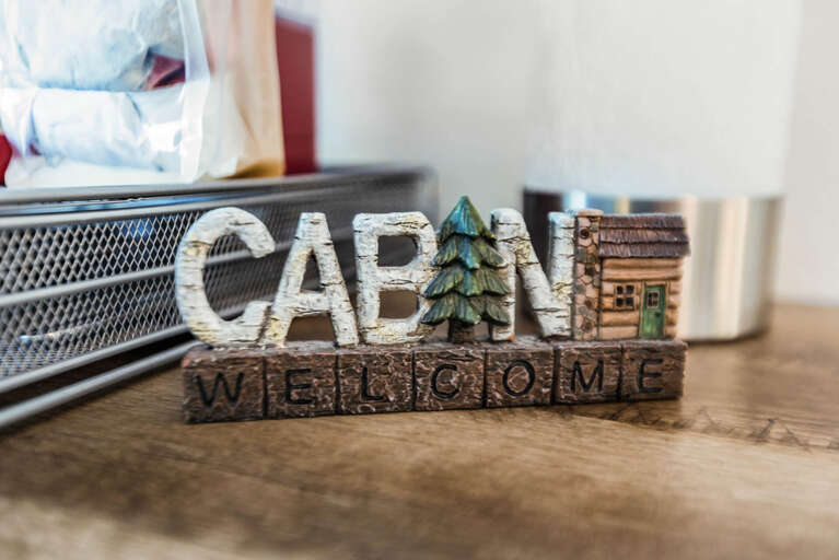 A charming cabin-themed welcome sign greets you, setting a cozy, rustic tone for your stay in this thoughtfully decorated space.