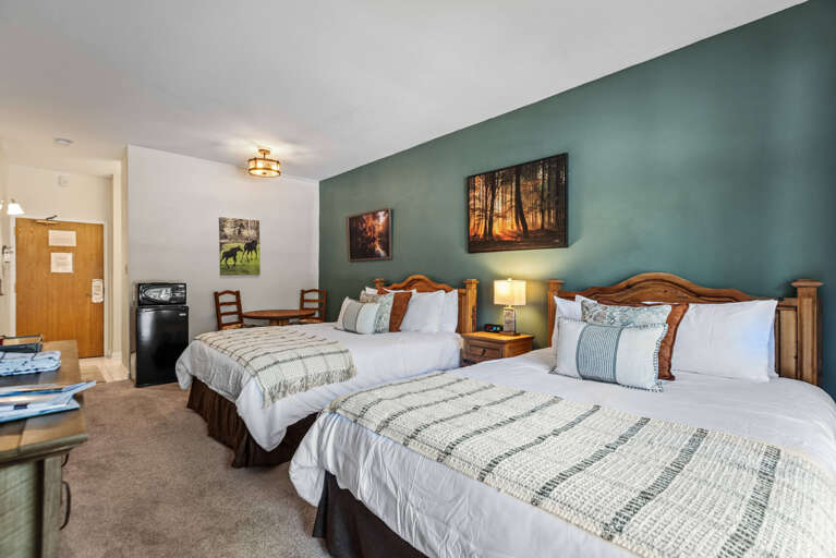 Sink into plush beds with crisp linens and let the calming sage accent wall help you unwind. Your cozy retreat awaits, complete with thoughtful touches for a restful stay.