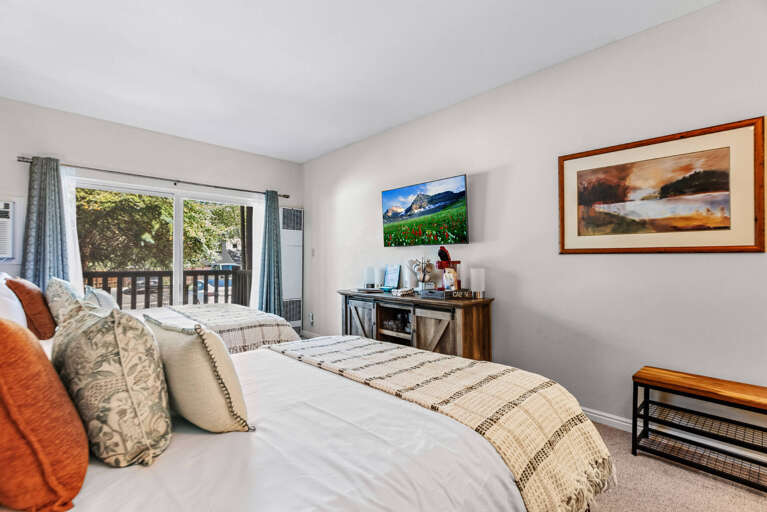 Sink into crisp linens and plush pillows in your private bedroom retreat, where natural light streams through the window and peaceful comfort awaits after a day of adventure.