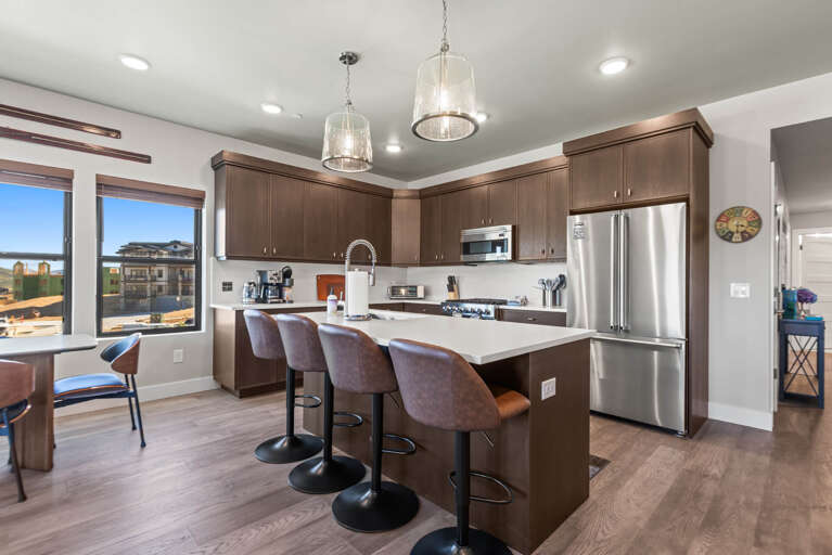 Your modern kitchen invites you to prepare meals together at the spacious island, surrounded by rich cabinetry and gleaming appliances, all bathed in natural light from oversized windows.