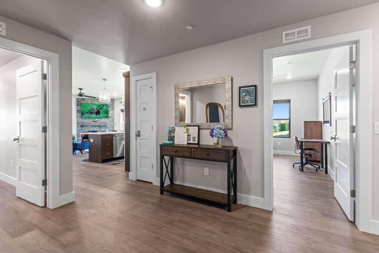 Your private hallway opens to inviting spaces throughout, from the bright living areas ahead to your personal office with a view on the right. Clean lines, warm wood floors, and thoughtful touches create a welcoming, connected home.