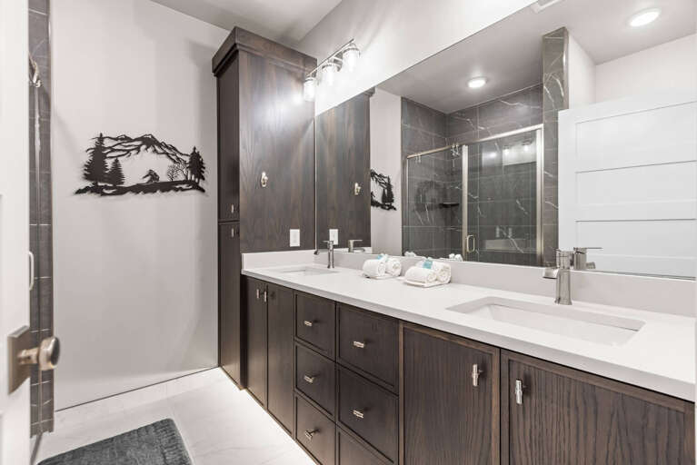 Your private spa-like bathroom features a sleek double vanity, modern walk-in shower, and rich wood cabinetry—perfect for unwinding after a day of adventure.