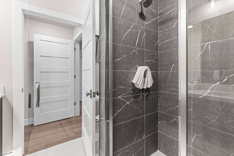 Step into your private sanctuary with a stunning walk-in shower wrapped in elegant marble tile and a fresh towel waiting just for you.