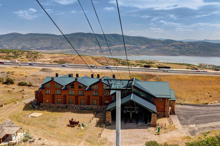 A distinctive lodge-style property sits along a scenic highway, with sweeping mountain and reservoir views defining the surrounding landscape.