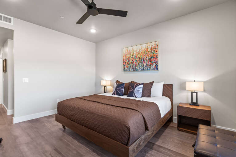 Step into your serene retreat, where a plush bed awaits beneath a gently spinning ceiling fan and warm bedside lighting invites you to unwind.