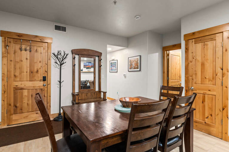 Gather around this warm wood dining table where you'll share meals and stories after your mountain adventures. The open layout connects you to cozy spaces beyond.