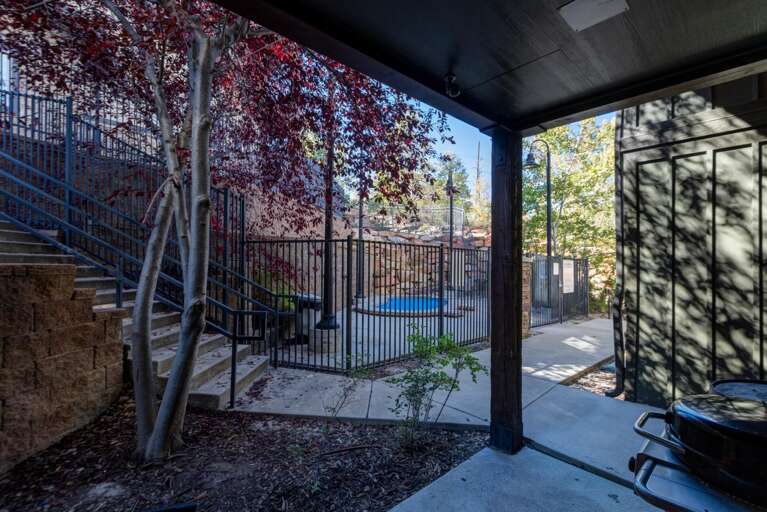 Step through your private entrance to find a peaceful courtyard space framed by vibrant foliage and a glimpse of the hot tub beyond the sleek fencing.