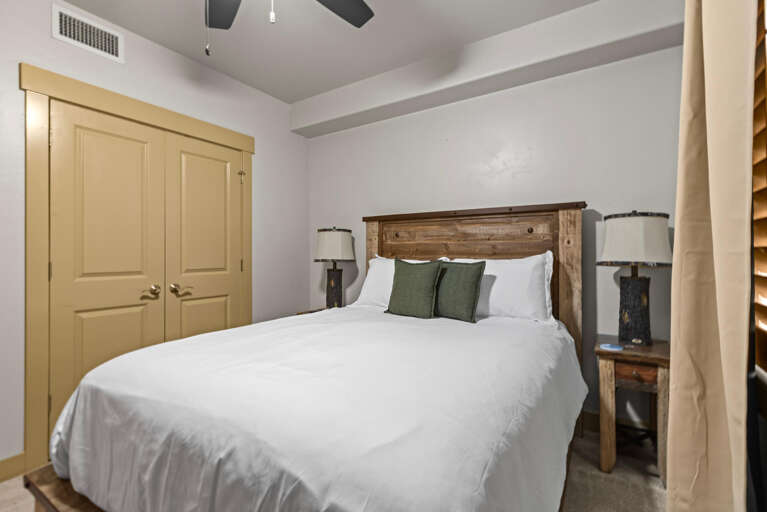 Sink into crisp white linens and rustic charm in this serene bedroom. The handcrafted wood headboard and gentle ceiling fan invite restful nights, while soft lighting and calming earth tones create your peaceful retreat.