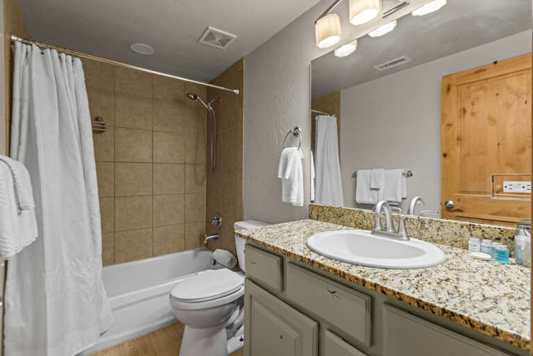 Shared bathroom with a spacious tub-shower combo, plush towels, and a granite vanity. Everything you need for a refreshing morning or a relaxing soak after a day of adventure.