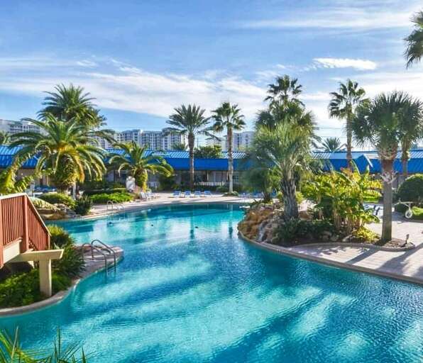 Swimming Pool Surrounded By Palm Trees And Buildings