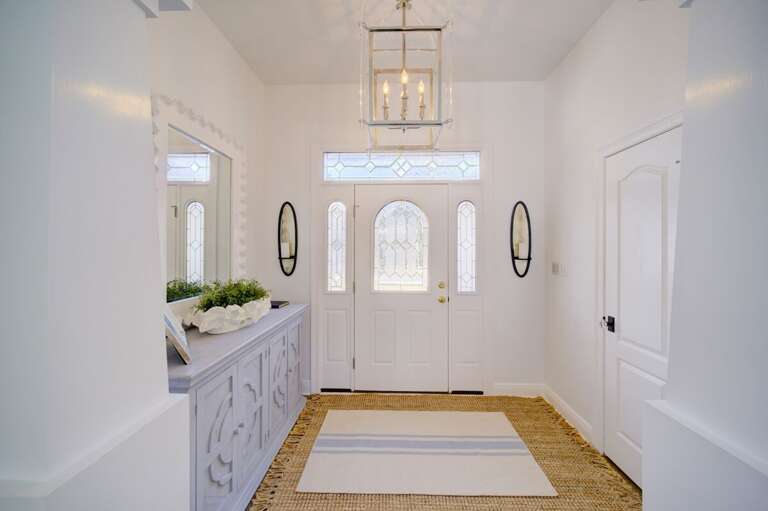 White Entryway With Mirror And Chandelier