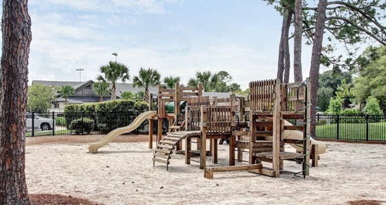 Wooden Playground With Slides Surrounded By Sand And Trees