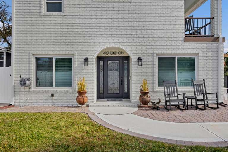 White-walled Residence With Green Shutters, Arched Doorway, And Outdoor Seating