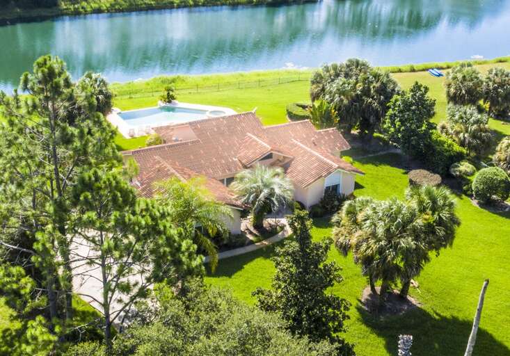 Aerial View Of A Lakeside Residential Building Surrounded By Lush Greenery