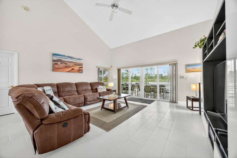 Bright Room With Brown Reclining Sofa, Geometric Coffee Table, Large Windows, And Ceiling Fan