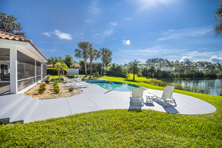 Poolside Loungers Beside Blue Waters, Lush Lawn Leading To Lake