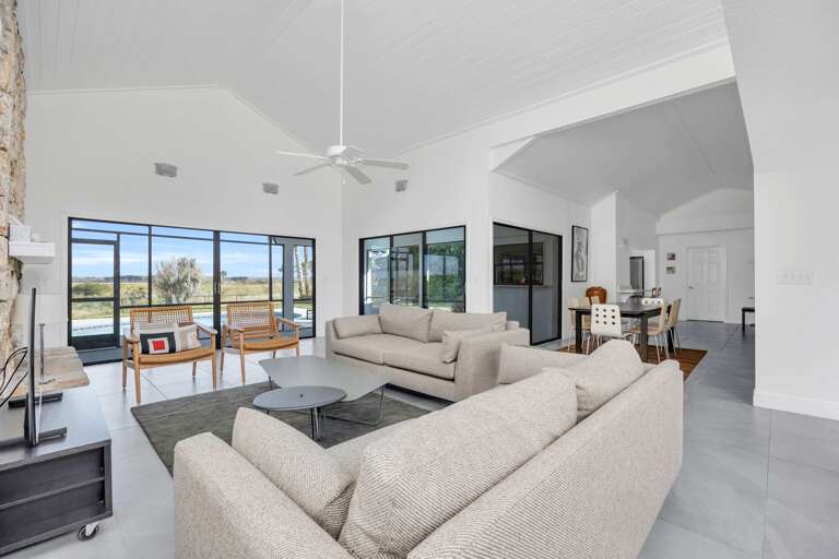 Spacious Living Room With Sofas, Large Windows, And Dining Area