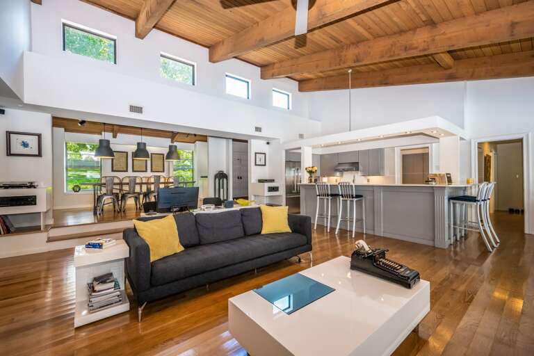 Spacious Living Space With Sleek Sofa, Stylish Stools, And Sunlit Setting