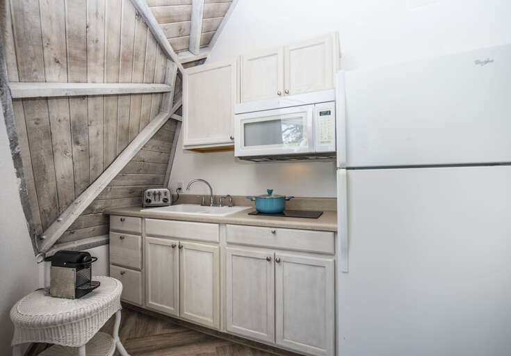 Compact Corner Kitchen With Light Cabinets Under Slanted Ceiling