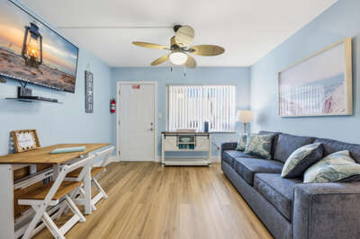 Bright coastal living room with comfortable seating, Smart TV, and dining area—perfect for relaxing during your Florida beach vacation.