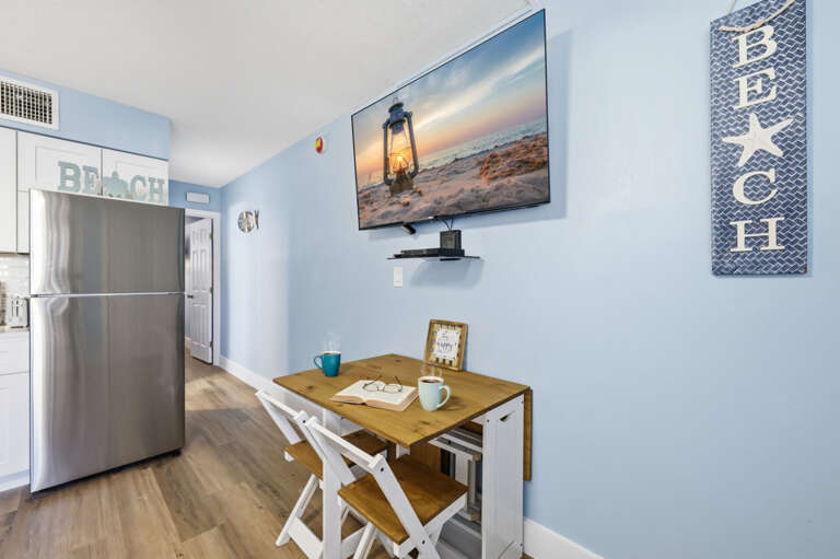 Beach-inspired dining space with Smart TV and easy access to the kitchen, offering a convenient setup for your coastal getaway.