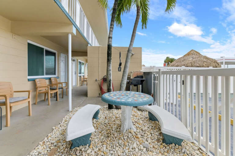 Tropical outdoor seating area with community BBQ grill nearby, offering a relaxing spot to dine and unwind during your Florida getaway.