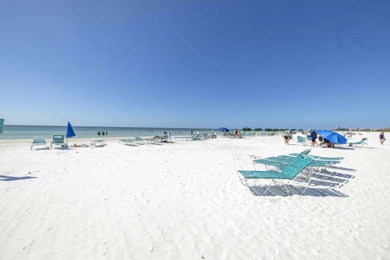 Sandy Shore Sprinkled With Sunbathers And Sea Shades