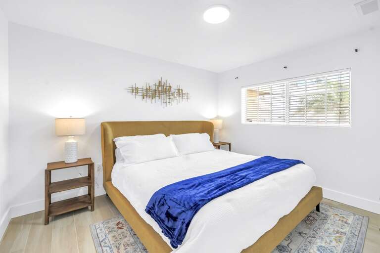 Cozy queen bedroom with soft bedding, warm lighting, and coastal wall décor. A relaxing space for a perfect night's sleep after exploring Siesta Key.