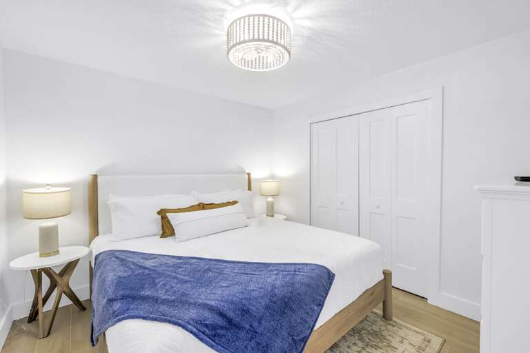 Elegant queen bedroom with modern lighting, plush bedding, and ample closet space. Designed for both comfort and style.