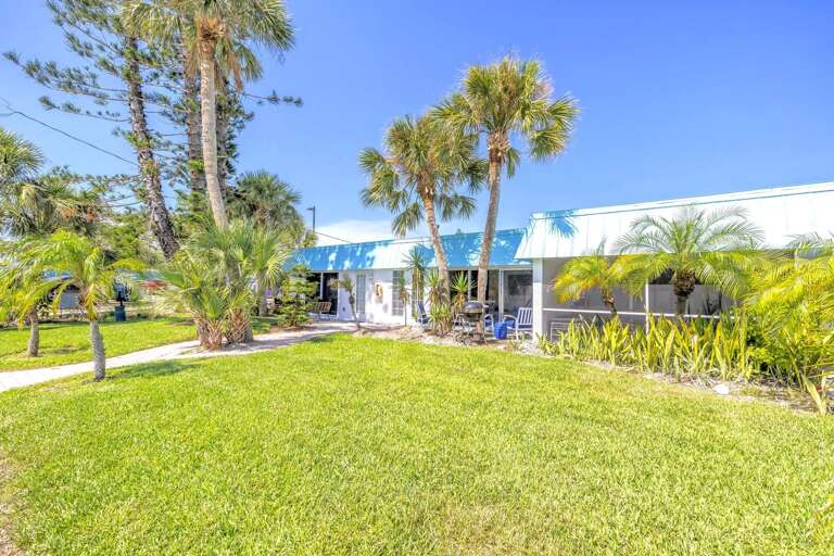 Relax in the expansive front lawn surrounded by palm trees and tropical plants. A peaceful outdoor space in the heart of Siesta Key Village.