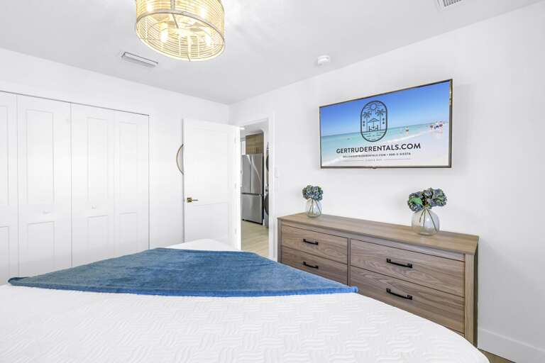 Spacious king bedroom featuring a flat-screen TV, dresser, and closet storage. Perfect for unwinding after a day at Siesta Key Beach.