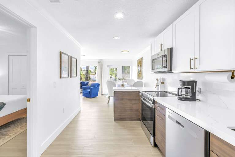 Spacious kitchen with white cabinetry and stainless steel appliances opening into the living area. Designed for comfort and connection during your vacation.