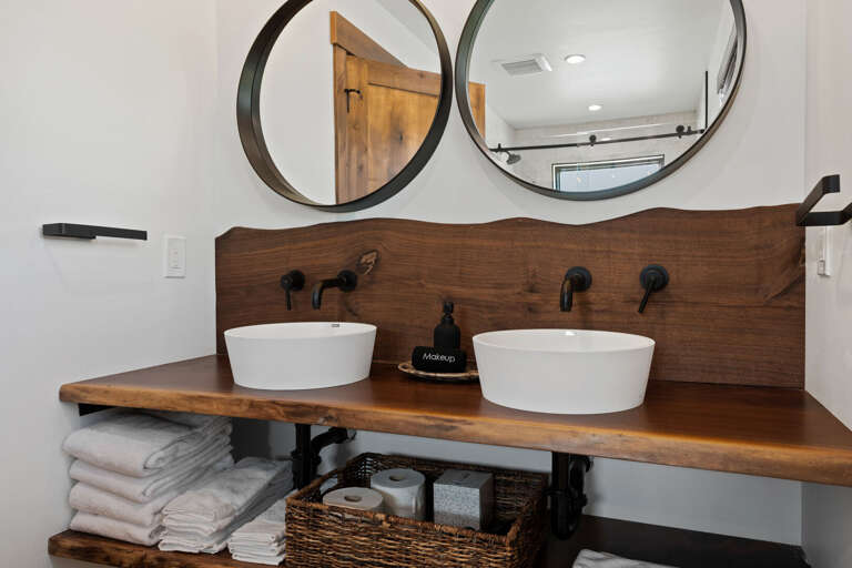 Downstairs en-suite bath includes custom live edge wood vanity and 2 sinks.