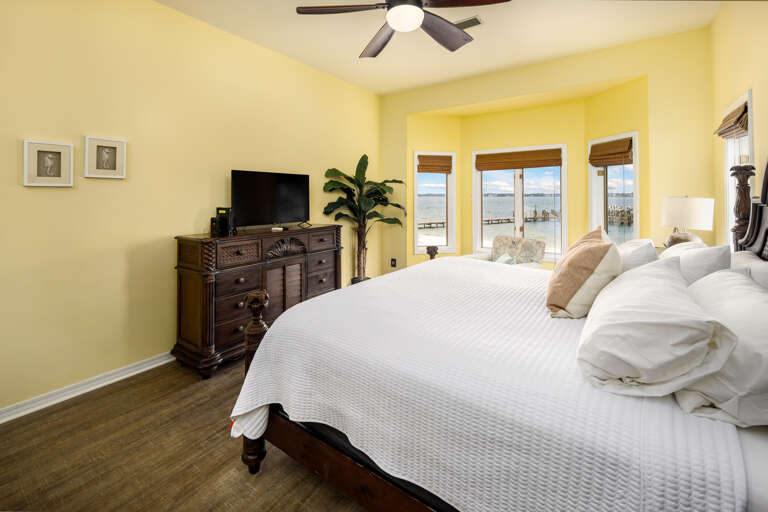 Master bedroom with king size bed, TV, and waterfront views