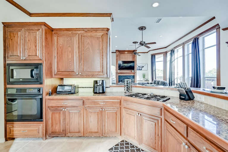 Kitchen with built-in microwave, oven, gas stovetop, as well as toaster oven, air fryer, spice rack, knife block and digital food scale on countertops