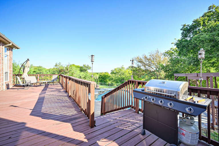 Large deck overlooking pool and backyard; propane gas grill on deck for grilling out