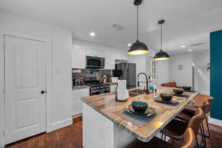 Bar seating area with 4 bar stools and full kitchen, view toward entry workspace back toward hallway to bedrooms